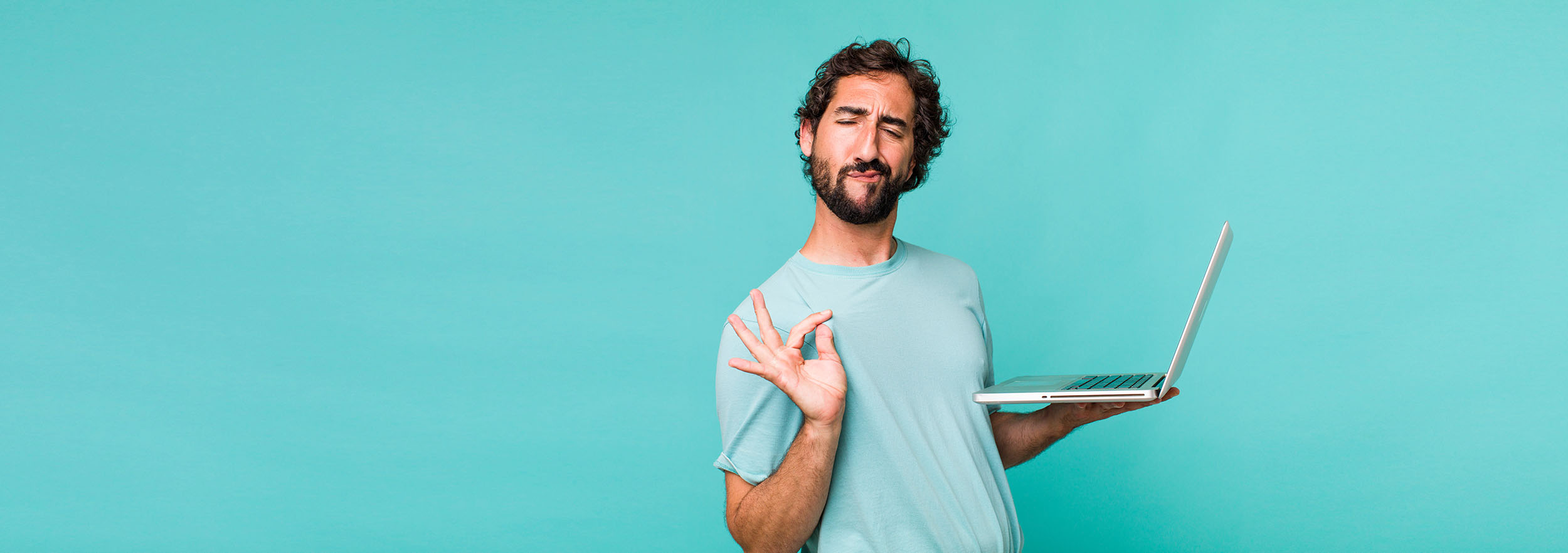 Young man holding a laptop while giving an "OK" hand gesture