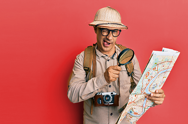Man wearing a adventurer outfit holding a map against a red background